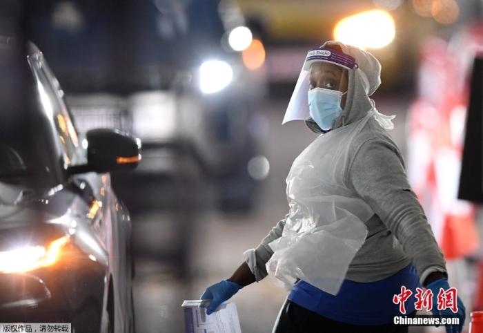 當(dāng)?shù)貢r(shí)間12月18日，英國(guó)政府公布的數(shù)據(jù)顯示，當(dāng)天英國(guó)新增奧密克戎毒株感染病例10059例。鑒于奧密克戎毒株感染病例激增，住院人數(shù)不斷上升，倫敦市長(zhǎng)宣布倫敦進(jìn)入“重大事故”狀態(tài)。圖為倫敦的一個(gè)免下車檢測(cè)中心，一名醫(yī)務(wù)工作者正準(zhǔn)備對(duì)司機(jī)進(jìn)行核酸檢測(cè)。