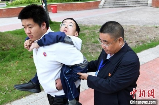 朱金祥背著鐘華強(qiáng)去教室上課的路上，也經(jīng)常碰到值班的校領(lǐng)導(dǎo)和老師前來搭把手。 卓忠偉 攝