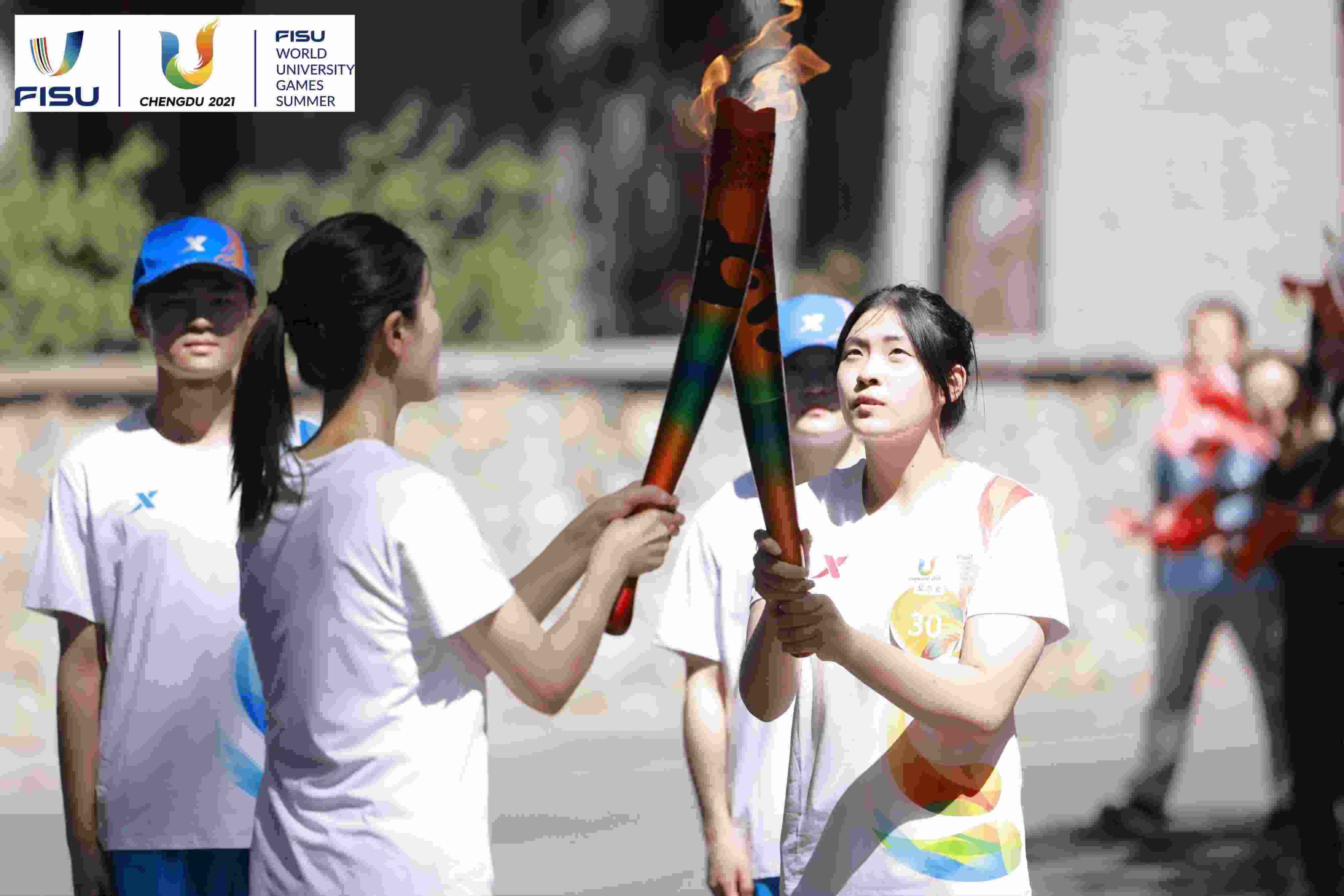 兩名大運(yùn)會(huì)火炬手進(jìn)行火炬?zhèn)鬟f。 圖片來源：成都大運(yùn)會(huì)執(zhí)委會(huì)供圖