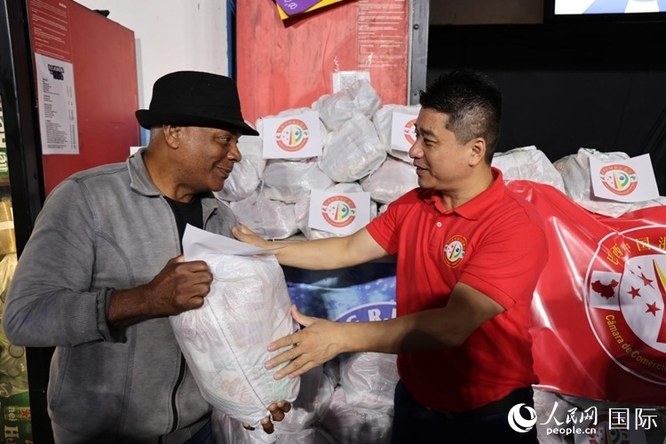 巴西中國浙江商會會長鄭俠茂向社區(qū)居民轉(zhuǎn)交捐贈物資。人民網(wǎng)記者 時元皓攝
