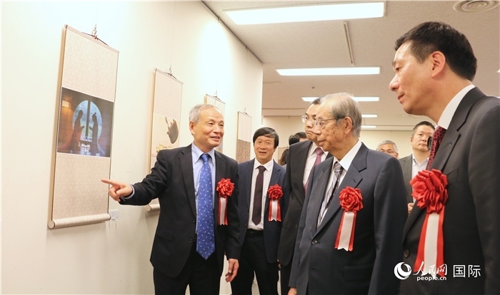 “湖州印象”攝影展主創(chuàng)、世界華人攝影協(xié)會副會長馮學敏向吳江浩大使、福田康夫前首相等嘉賓介紹展出作品。（人民網(wǎng) 許可攝）