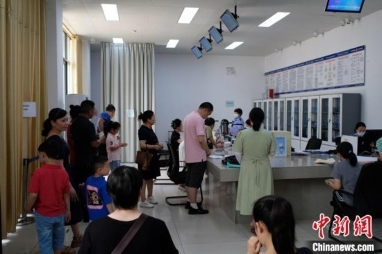 圖為在戶籍辦證廳內(nèi)排隊(duì)等待的家長(zhǎng)和孩子。劉俊聰 攝