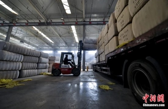 新疆喀什綜合保稅區(qū)，喀什啟路國(guó)際貿(mào)易有限公司的倉(cāng)庫(kù)內(nèi)，工人正在裝載從塔吉克斯坦和烏茲別克斯坦進(jìn)口的棉花。劉新攝