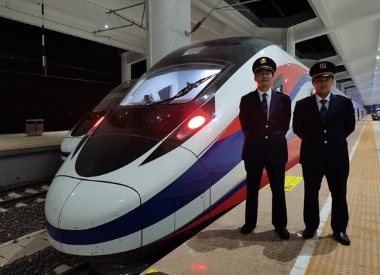 劉銀能（右一）與中國師父鄔俊鴻在動車組前合影。受訪者供圖