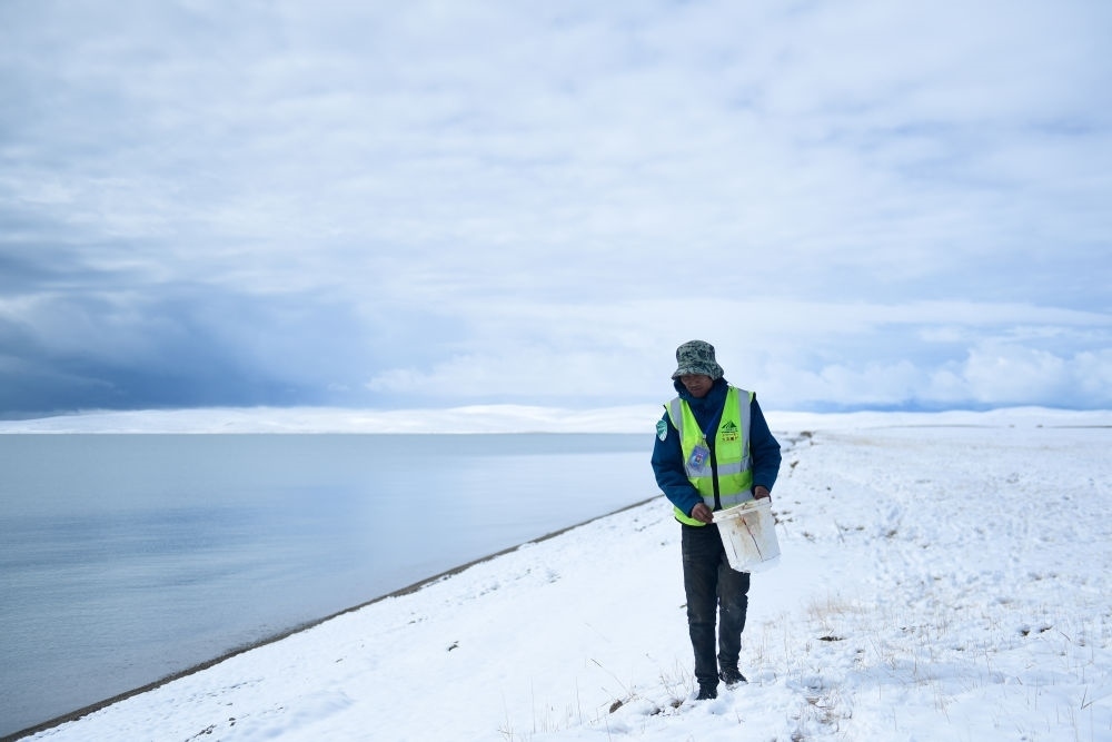 2021年10月20日，在青海省果洛藏族自治州瑪多縣扎陵湖鄉(xiāng)勒那村，三江源國(guó)家公園黃河源園區(qū)生態(tài)管護(hù)員在扎陵湖邊撿拾垃圾。新華社記者 張龍 攝