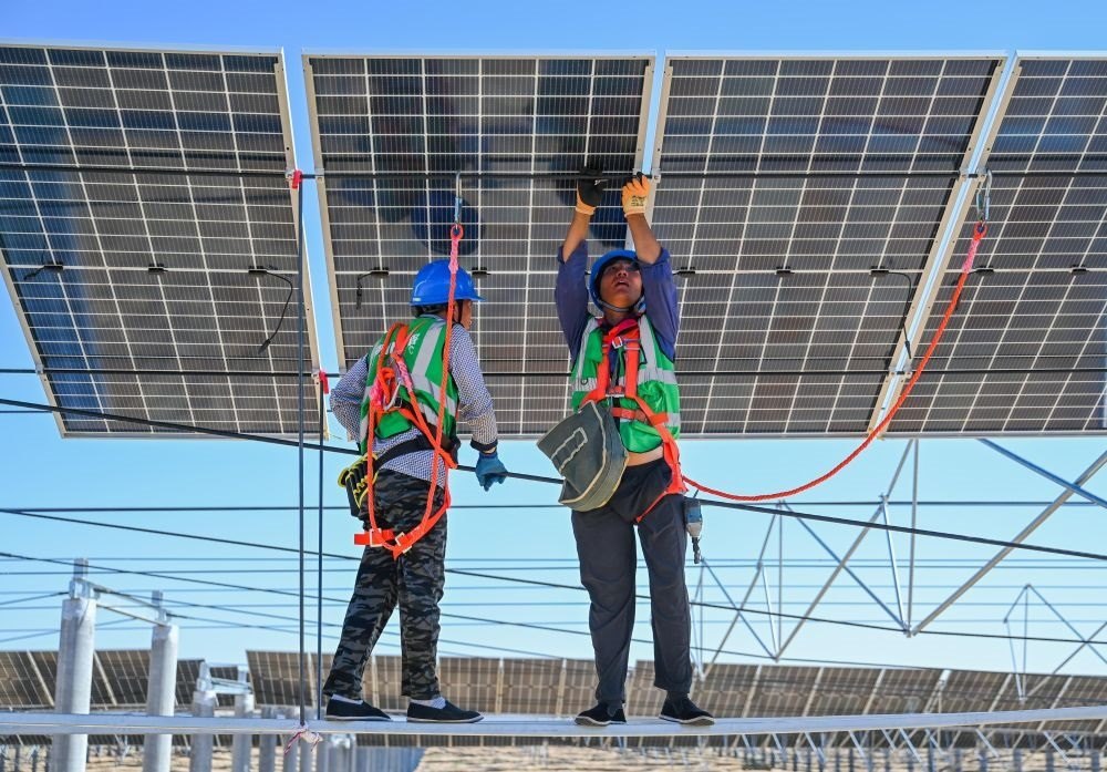 2023年7月22日，工人在位于內(nèi)蒙古杭錦旗庫(kù)布其沙漠億利生態(tài)示范區(qū)的蒙西基地庫(kù)布其200萬(wàn)千瓦光伏治沙項(xiàng)目工地安裝光伏板。新華社記者 劉磊 攝