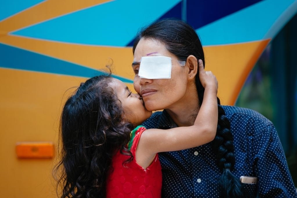 2019年3月15日，在柬埔寨磅湛省醫(yī)院，即將接受白內(nèi)障手術(shù)的患者孫美樂接受女兒的親吻祝福。在接受了中國醫(yī)療隊的白內(nèi)障義診手術(shù)后，她的視力逐步恢復(fù)，生活有了新的光明和希望。