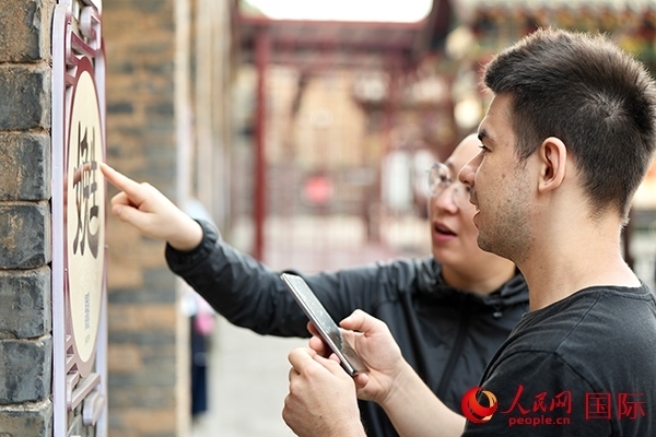 選手安德烈（俄羅斯）在老師指導(dǎo)下學(xué)習(xí)墻壁上張貼的生僻字。人民網(wǎng) 盧鵬宇攝