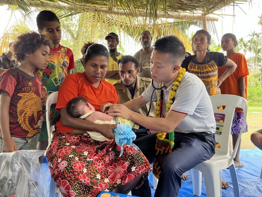 2023年8月5日，在巴布亞新幾內(nèi)亞中央省的一個(gè)村莊里，第12批援巴新中國(guó)醫(yī)療隊(duì)副隊(duì)長(zhǎng)、新生兒科副主任醫(yī)師劉振球?yàn)楫?dāng)?shù)貗雰郝?tīng)診檢查。新華社發(fā)（第12批援巴新中國(guó)醫(yī)療隊(duì)供圖）