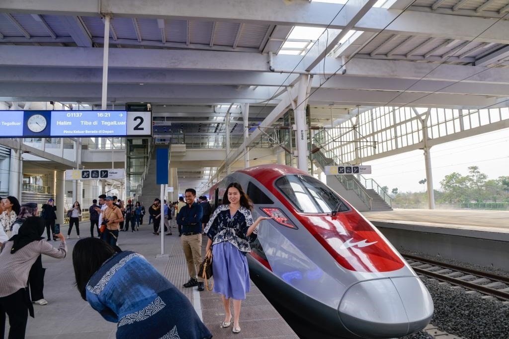 10月17日，在印度尼西亞萬隆德卡魯爾站，乘客在站臺上和雅萬高鐵高速動(dòng)車組列車合影。