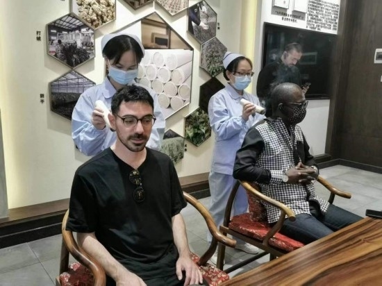 2023“一帶一路”媒體合作論壇聯(lián)合采訪團團員在九牛草展示館體驗艾灸。（本報記者 黃超攝）