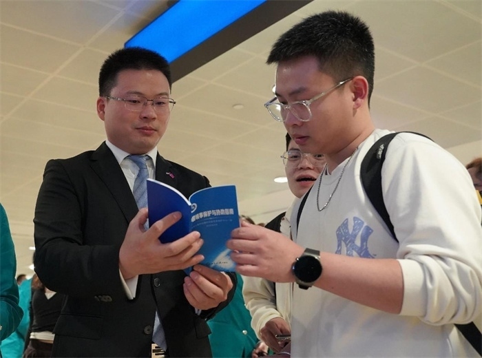 工作人員（左一）在發(fā)放《中國(guó)領(lǐng)事保護(hù)與協(xié)助指南》。 中國(guó)駐迪拜總領(lǐng)事館供圖