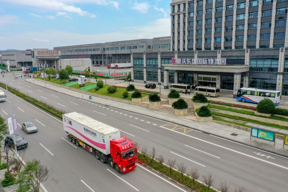 2023年10月11日，滿載筆記本電腦配件、發(fā)電機組件等產(chǎn)品的西部陸海新通道跨境公路班車從重慶南彭公路保稅物流中心駛出，將途經(jīng)廣西憑祥，直達越南（無人機照片）。新華社記者 黃偉 攝