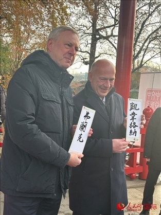 柏林市長韋格納（右）、動物園監(jiān)事會主席布魯克曼（左）手持中國文化中心工作人員現(xiàn)場手書的中文名字。人民網(wǎng)記者 徐馨攝