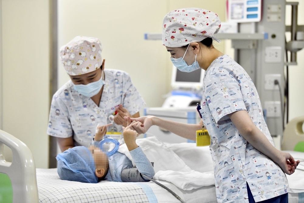 在山東省棗莊市婦幼保健院兒童ICU病房，醫(yī)護人員為完成靶向治療藥物諾西那生鈉的4歲脊髓性肌萎縮癥患兒加油鼓勁（2022年1月1日攝）。諾西那生鈉注射液是我國首個獲批治療脊髓性肌萎縮癥的進口藥物，2019年進入中國市場時，每針價格近70萬元。在2021年國家醫(yī)保目錄藥品談判中，以3.3萬元每針的價格進入新版醫(yī)保藥品目錄。新華社記者 郭緒雷 攝