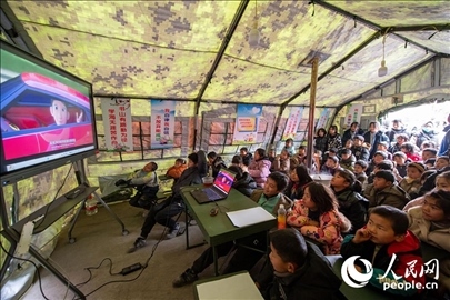 12月22日，在積石山縣大河家鎮(zhèn)大河村安置點，陸軍76集團軍某旅搭建的“臨時學?！眱?，小朋友正在看動畫片。人民網記者 翁奇羽攝