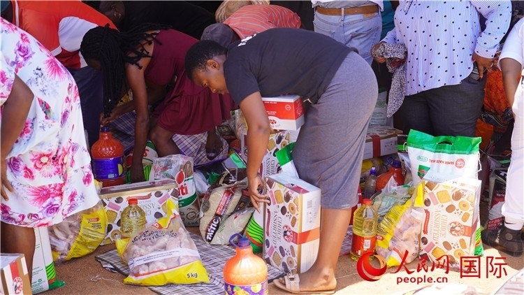 當(dāng)?shù)厣鐓^(qū)家庭領(lǐng)取物資。人民網(wǎng) 張茜攝