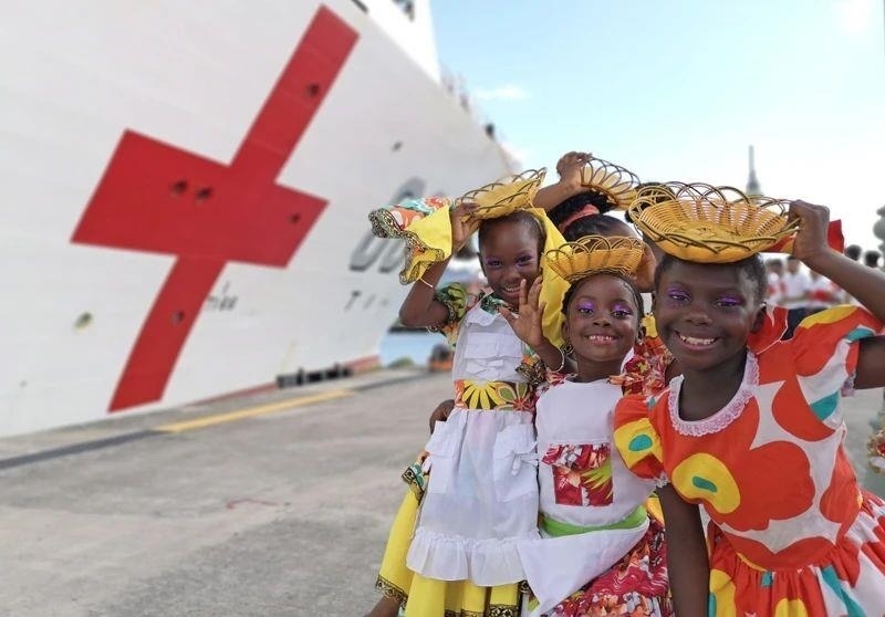 2018年10月，在安提瓜和巴布達首都圣約翰，當?shù)匦∨笥焉泶﹤鹘y(tǒng)服裝歡迎中國海軍“和平方舟”醫(yī)院船首次到訪。