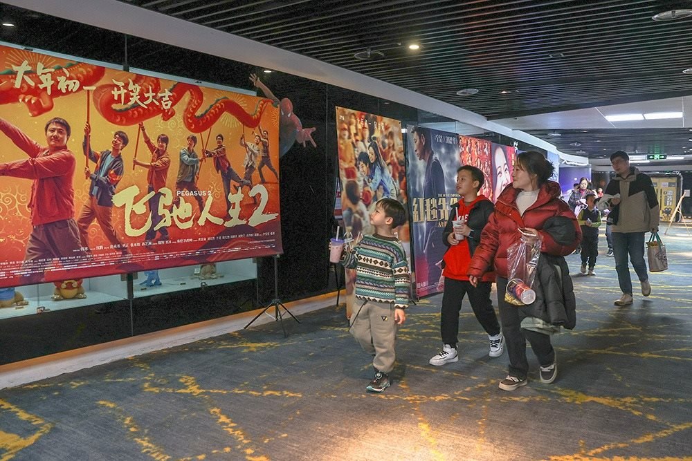 △ 2024年2月16日，在江西贛州一家電影院，觀眾從春節(jié)檔電影的宣傳展板前走過。