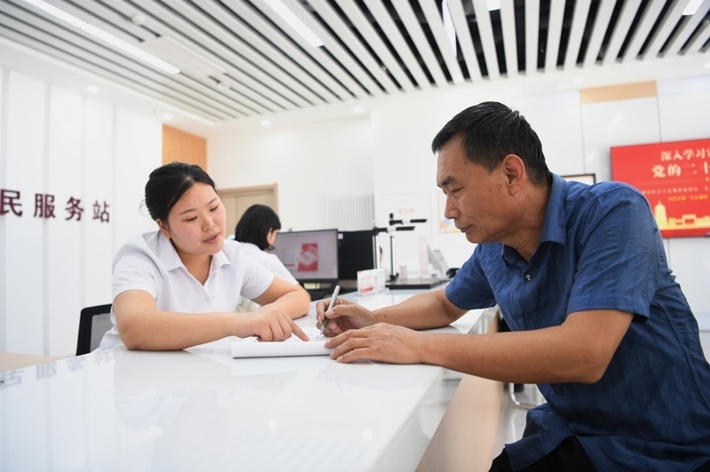2023年5月23日，河北雄安新區(qū)容東片區(qū)南文營社區(qū)居民（右）在社區(qū)便民服務(wù)站辦理業(yè)務(wù)。