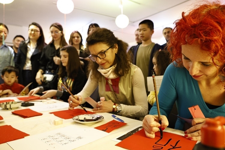 羅馬尼亞觀眾學(xué)習(xí)用毛筆寫“?！弊帧Ｖ袊?guó)文化中心供圖