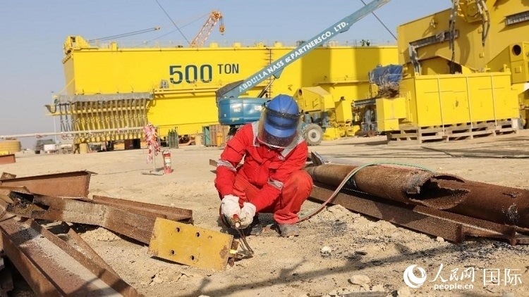 工人正在龍門吊吊裝現(xiàn)場(chǎng)切割金屬件。人民網(wǎng)記者管克江攝