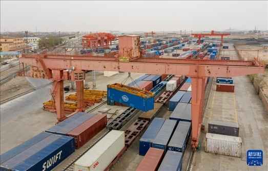 4月21日，二連浩特鐵路口岸龍門吊吊裝中歐班列集裝箱（無人機照片）。 新華社發(fā)（張海峰攝）