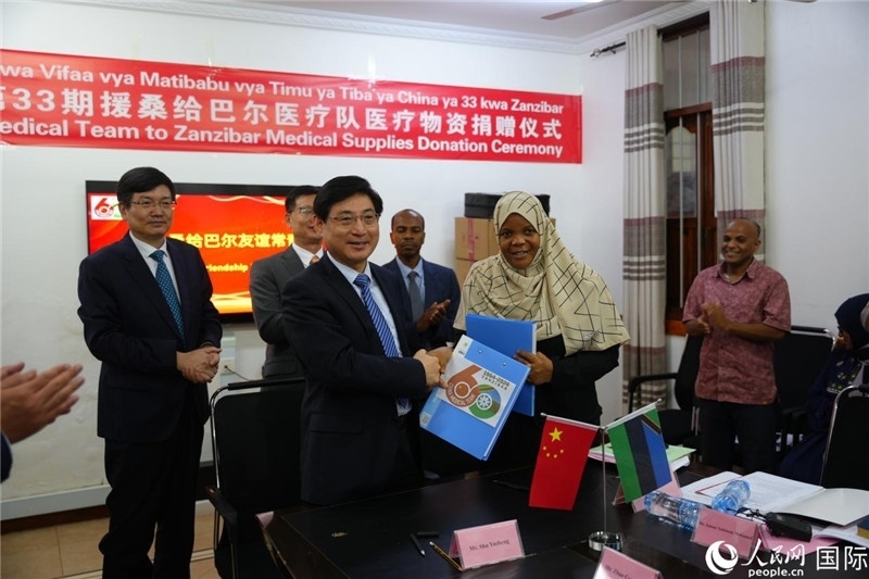 江蘇省蘇北人民醫(yī)院黨委書記束余聲與桑衛(wèi)生部首席秘書哈比巴交換捐贈(zèng)書。中國(guó)援桑醫(yī)療隊(duì)供圖