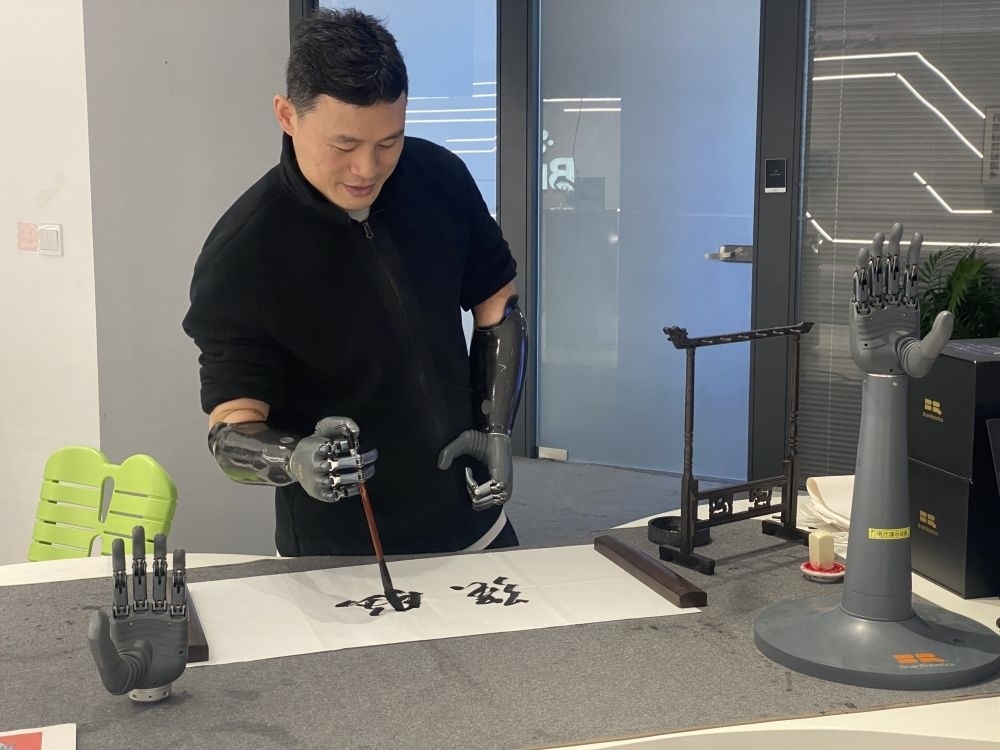 2024年3月29日，在浙江強(qiáng)腦科技有限公司展廳內(nèi)，失去雙手的產(chǎn)品體驗(yàn)官倪敏成依靠智能仿生手寫(xiě)毛筆字。新華社記者 魏一駿 攝