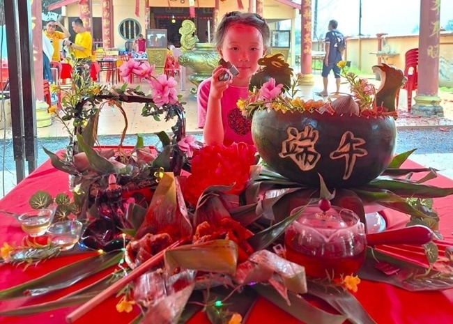 小朋友展示學(xué)裹粽子的成品照。組委會供圖