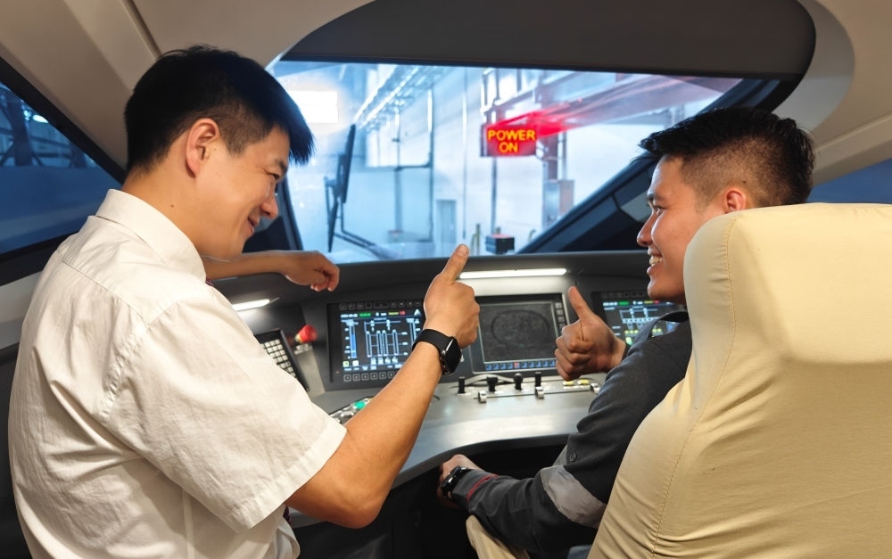 2023年8月25日，在印度尼西亞萬隆的雅萬高鐵德卡魯爾動車所內(nèi)，中國師傅穆振（左）向印尼火車司機塞蒂亞萬講解動車組出庫前的上電作業(yè)。新華社記者 徐欽 攝