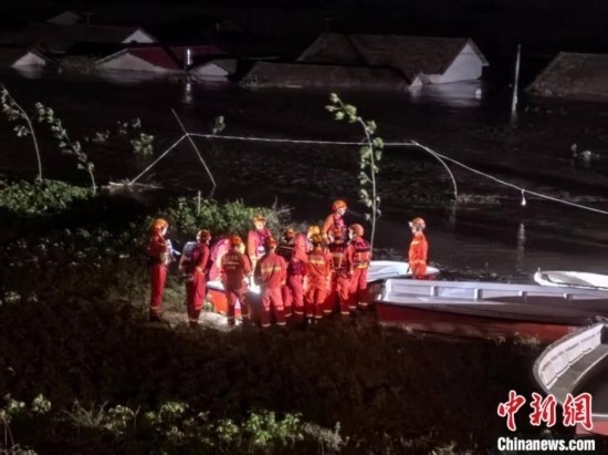  7月6日凌晨3時(shí)，在湖南岳陽(yáng)華容縣團(tuán)洲垸洞庭湖一線堤防，救援人員剛剛完成一次救援任務(wù)，遠(yuǎn)處是被淹的民房。中新社記者 白祖偕 攝