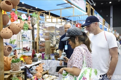 游客在蘭納博覽會特色展位上選購工藝品。人民網(wǎng)記者楊一攝