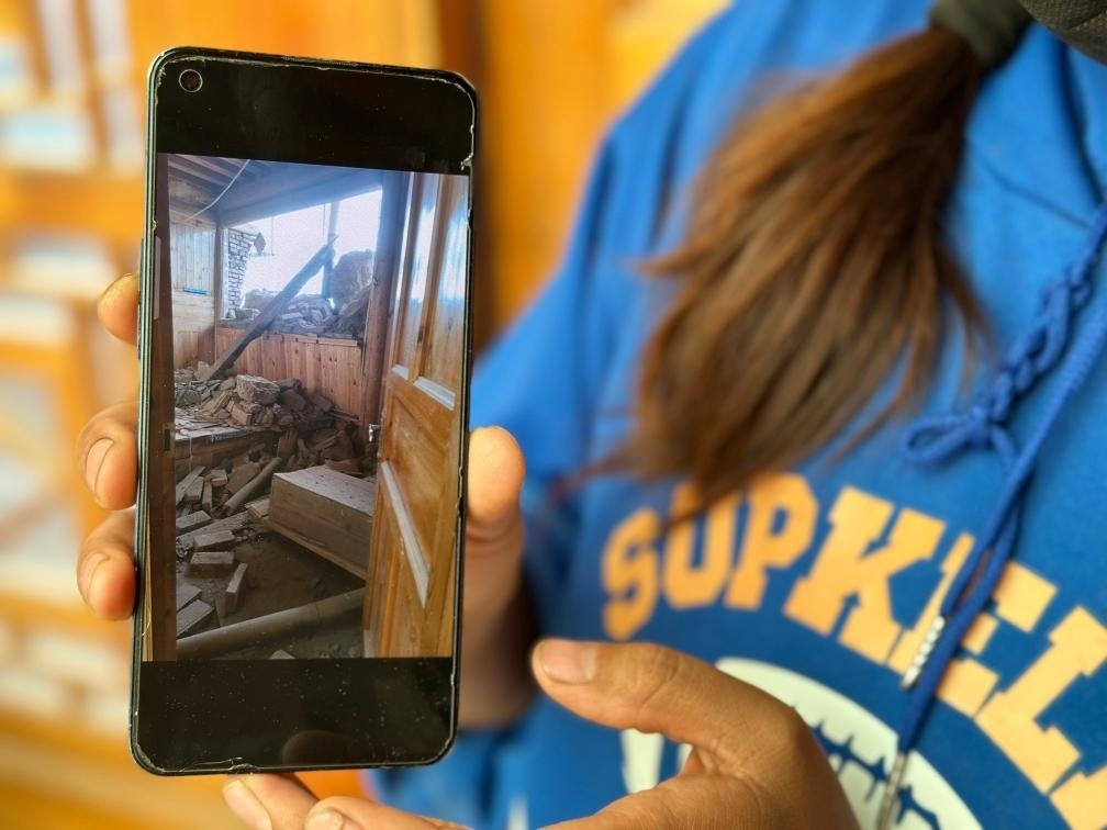 圖為7月17日拉毛東智在手機(jī)上找出地震后房屋受損的照片。新華社記者 張子琪 攝