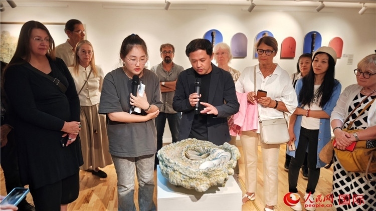 參展人、景德鎮(zhèn)陶瓷大學(xué)設(shè)計(jì)藝術(shù)學(xué)院副院長(zhǎng)余劍峰（中）向來(lái)賓介紹參展作品。人民網(wǎng)記者 殷淼攝