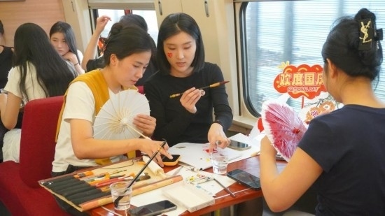 10月1日，旅客們在G1634次列車上給油紙傘作畫。新華社記者周義 攝