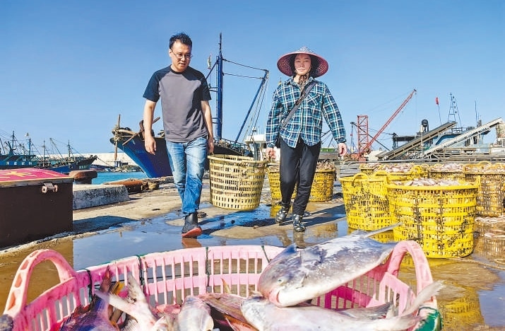 許小斌（左）和漁民一起搬運(yùn)海鮮。本報(bào)記者 付 文攝