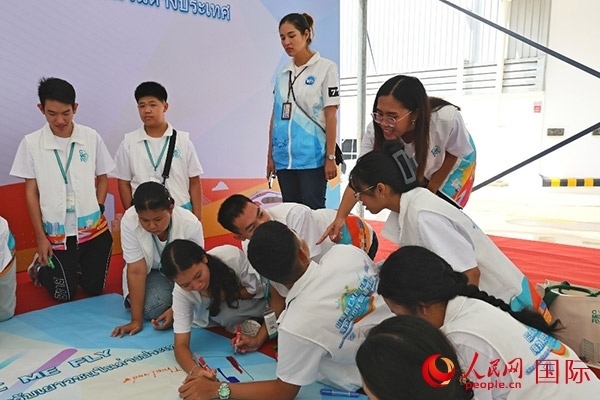 泰國學生在開營儀式展板上繪制圖案。人民網(wǎng)記者 白元琪攝