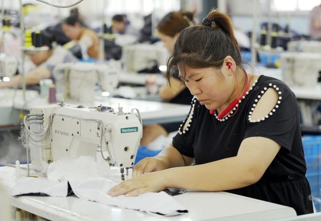5月20日，村民在李寨村服裝加工廠內(nèi)忙碌。河南省周口市沈丘縣馮營鎮(zhèn)李寨村地處豫東平原。近年來，乘著脫貧攻堅與鄉(xiāng)村振興政策的東風(fēng)，李寨村積極探索產(chǎn)業(yè)發(fā)展模式，通過“龍頭企業(yè)+村集體經(jīng)濟(jì)+農(nóng)戶”的方式，逐漸發(fā)展形成肉牛養(yǎng)殖、設(shè)施農(nóng)業(yè)、服裝加工、康養(yǎng)民宿等產(chǎn)業(yè)，以產(chǎn)業(yè)振興助力鄉(xiāng)村振興。新華社記者 李嘉南 攝