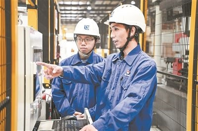 在廣西柳工機(jī)械股份有限公司生產(chǎn)車間內(nèi)，一名高級(jí)技師（右）給徒弟講解數(shù)控設(shè)備操作細(xì)節(jié)。新華社記者 曹祎銘攝