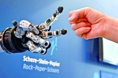 在德國漢諾威工博會上，參觀者與一款智能機器人進行“石頭剪子布”游戲。新華社發(fā)