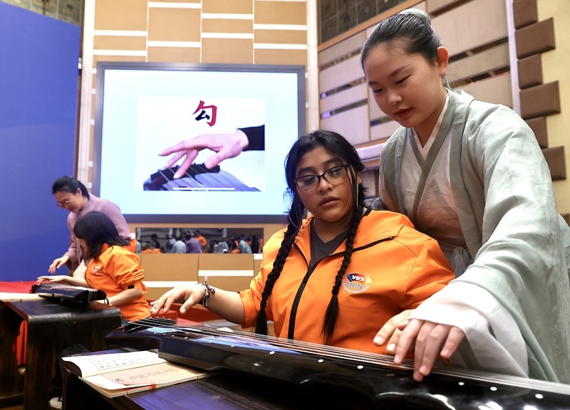 2024年3月20日，美國華盛頓州中學(xué)生代表團(tuán)北京大學(xué)交流活動在北京大學(xué)英杰交流中心舉行。圖為來自華盛頓州的中學(xué)生體驗古琴。