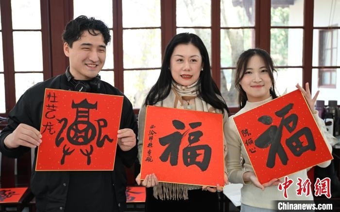 1月20日，外籍留學(xué)生和西泠印社社員李硯(中)展示各自創(chuàng)作的福貼。當(dāng)日，來自巴西、馬來西亞、加納、哈薩克斯坦的外籍留學(xué)生在浙江杭州西泠印社體驗(yàn)福貼、春聯(lián)和篆刻，感受古老的中國傳統(tǒng)文化。中新社記者 王剛 攝