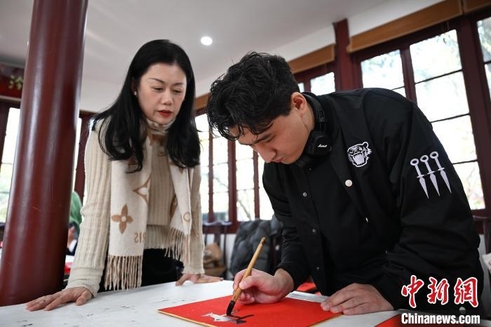 1月20日，外籍留學(xué)生在西泠印社社員李硯指導(dǎo)下寫福。當(dāng)日，來自巴西、馬來西亞、加納、哈薩克斯坦的外籍留學(xué)生在浙江杭州西泠印社體驗(yàn)福貼、春聯(lián)和篆刻，感受古老的中國傳統(tǒng)文化。中新社記者 王剛 攝