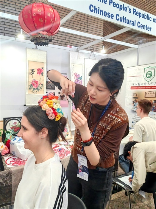 展覽正值羅馬尼亞迎春花節(jié)，國際中文教師志愿者潘婧穎向游客們介紹了國家非物質文化遺產(chǎn)——福建泉州的簪花文化。布加勒斯特大學孔子學院供圖。