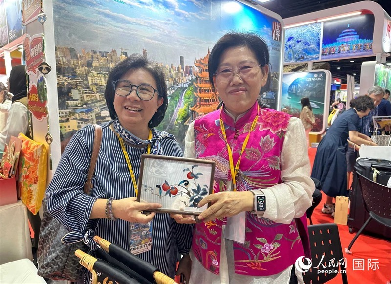 中國“大冶刺繡”傳承人劉小紅（右）參加泰國國際旅游展，向觀眾介紹中國非遺刺繡針法。人民網(wǎng)記者 簡承淵攝